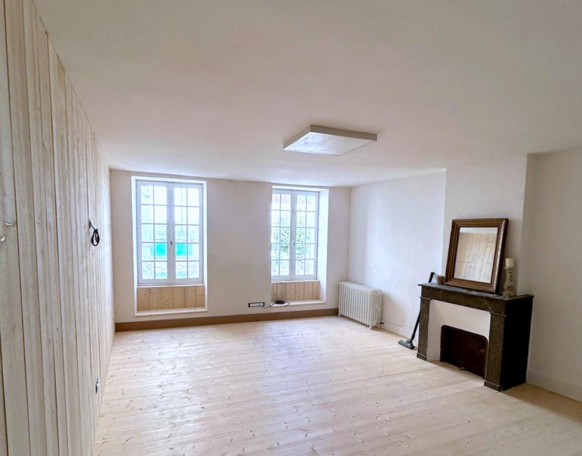 rénovation cellule commerciale - parquet, mur bois, placo, electricité Salle de séjour vide avec parquet clair et fenêtres laissant entrer la lumière.