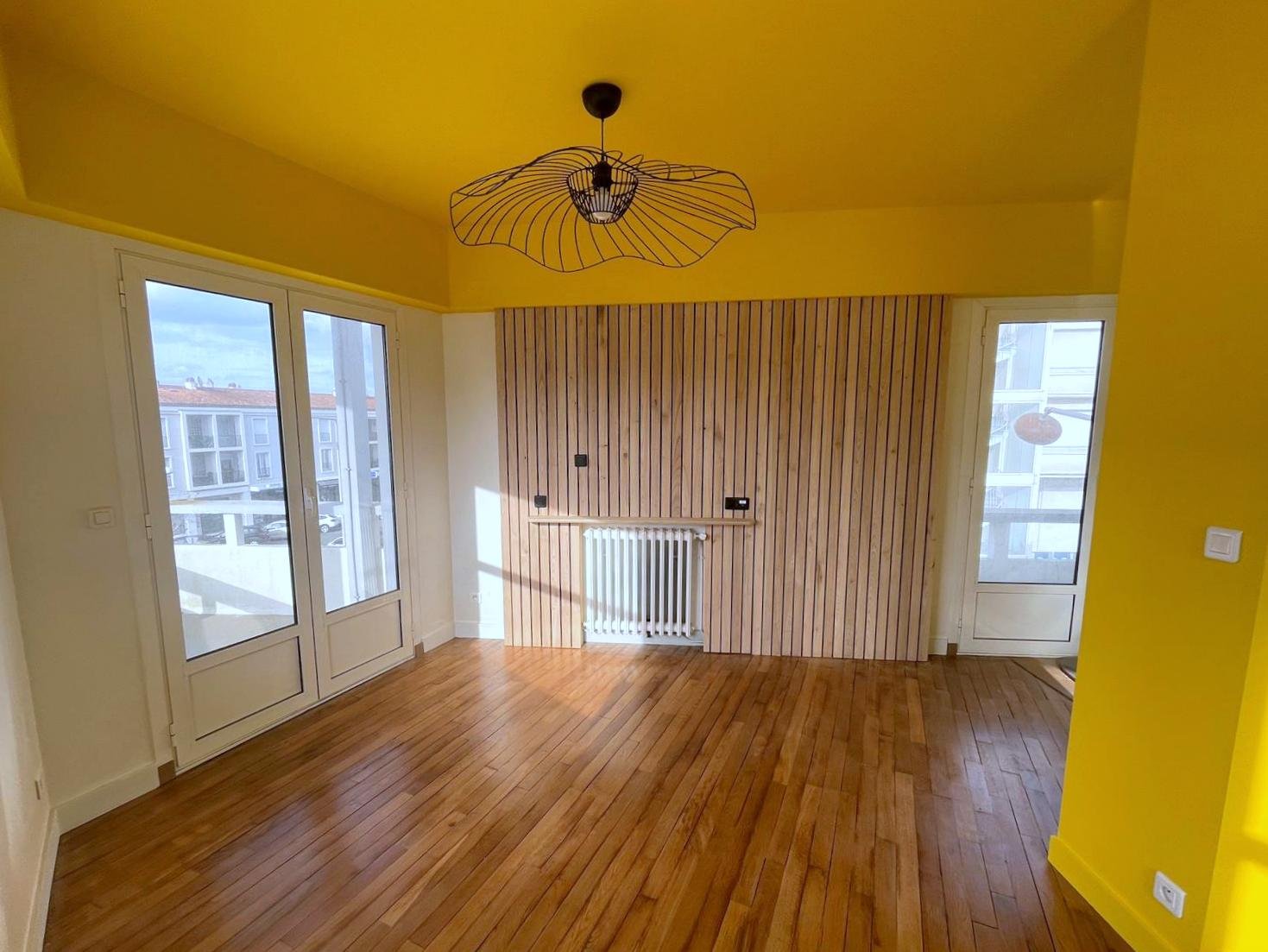 renovation appartement locatif royan Intérieur d'une pièce avec des murs jaunes et un parquet en bois lumineux.